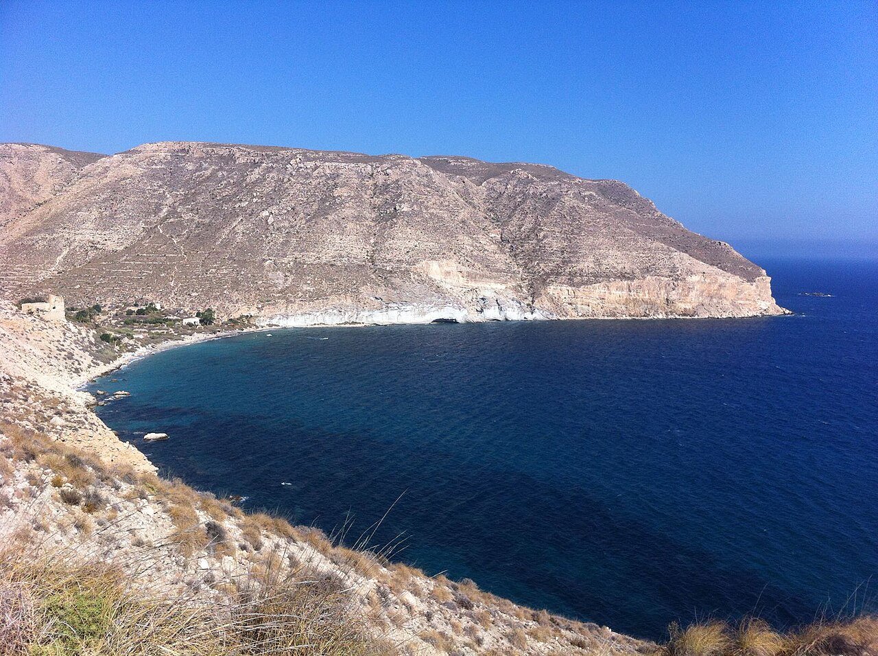 La ensenada de la Cala de San Pedro vista desde el camino, con el mar azul y los acantilados